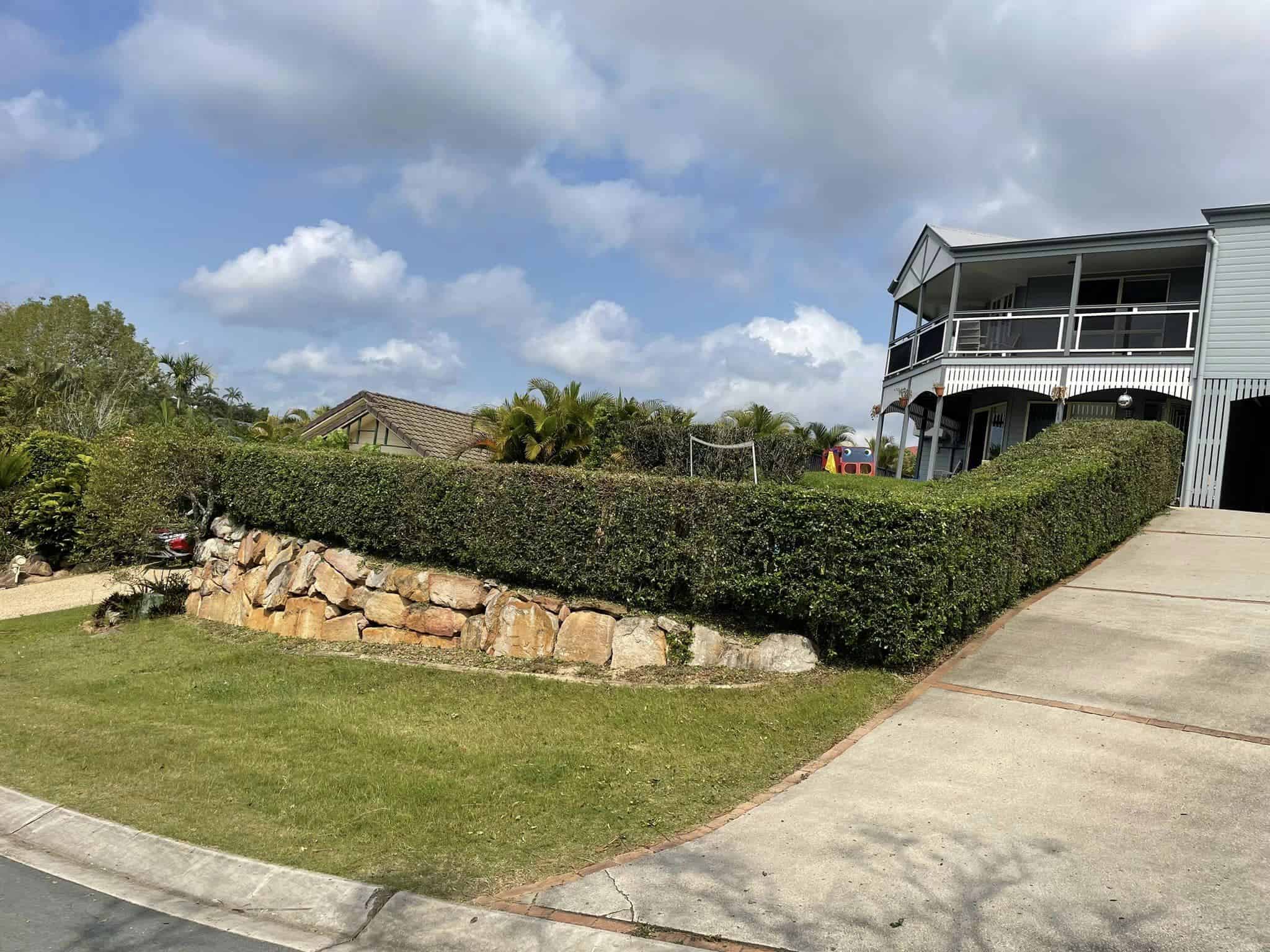 Modern house with large verandah, lush garden, cloudy sky